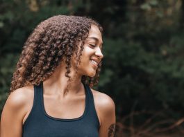 retire early retire young smiling woman in black tank top with curly hair New Year resolutions