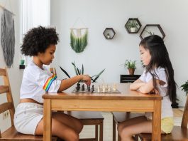 multiethnic thoughtful girls playing chess in modern room